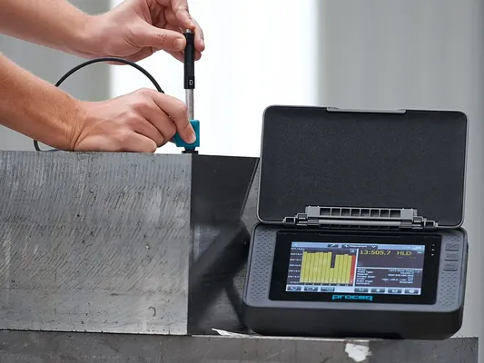 Técnico especializado utilizando equipo Equotip 550 Leeb para realizar medición de dureza en una superficie metálica en entorno industrial