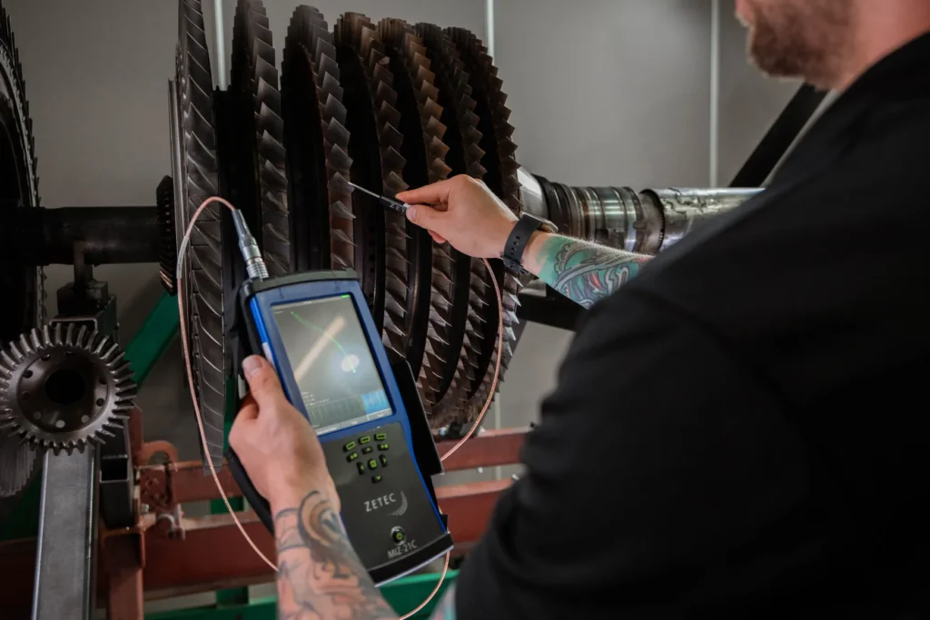 Imagen de un técnico realizando una prueba de corrientes de Eddy en una pieza metálica, utilizando un equipo portátil de inspección no destructiva.
