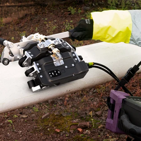 Un técnico con guantes de seguridad operando un equipo de ensayo avanzado en una tubería en campo, realizando inspecciones precisas para detectar anomalías.