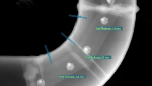 Radiografía industrial mostrando mediciones precisas del espesor de pared en una sección curva de tubería para control de calidad