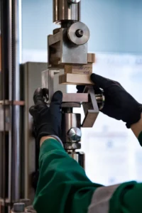 Manos enguantadas ajustan muestras de materiales compuestos en un equipo de pruebas para llevar a cabo Ensayos No Destructivos.
