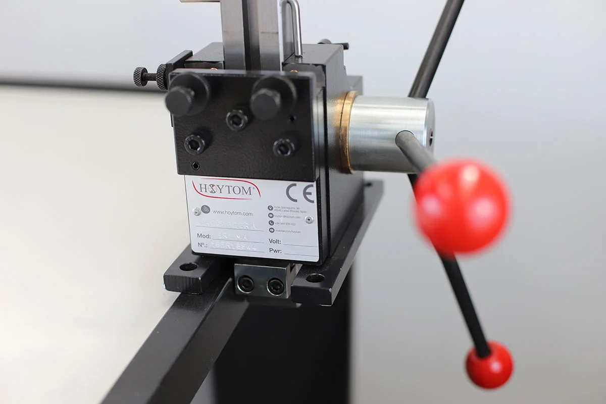 Una brochadora manual con su etiqueta de información técnica claramente visible y un brazo de palanca con una bola roja