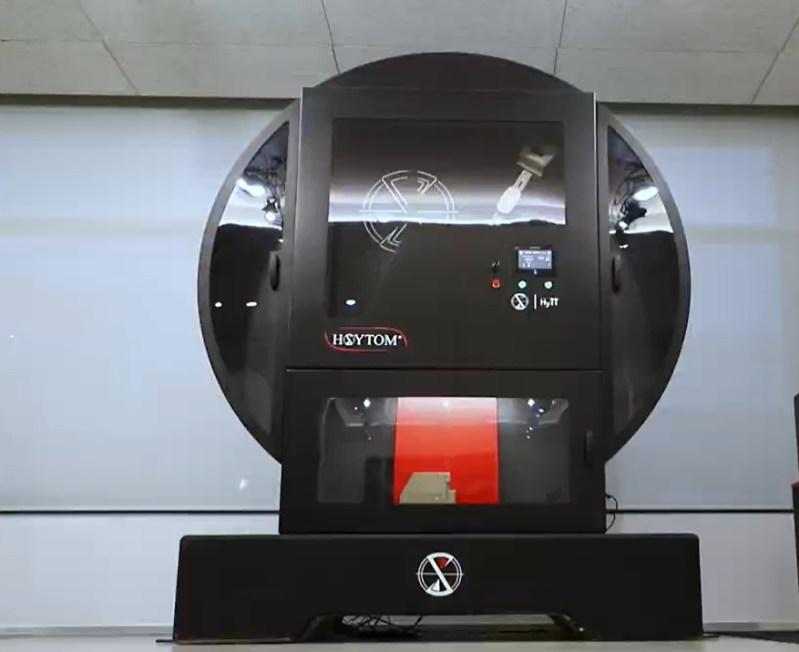 Vista frontal de una gran máquina de ensayo de impacto Hoytom con protección de seguridad y pantalla de control digital.