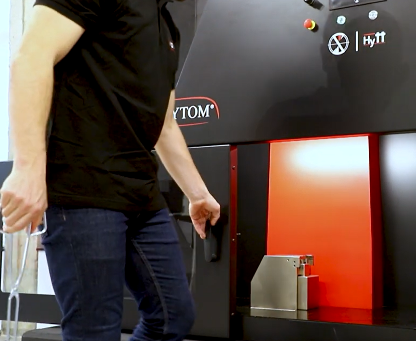 Un técnico carga con unas pinzas una probeta en el soporte de un péndulo Charpy de gran tamaño antes del ensayo.