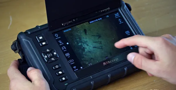 Operador utilizando la interfaz táctil de un sistema de videoscopia Mitcorp para analizar marcas en una superficie oscura.