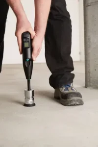 Técnico especializado utilizando un esclerómetro de impacto sobre un pavimento de hormigón para verificar su calidad