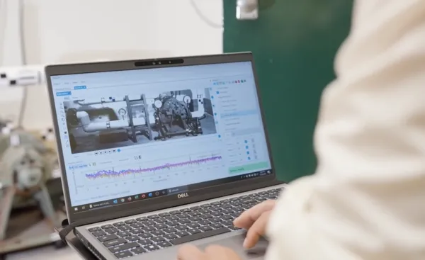 Un experto en mantenimiento de equipo usa una computadora portátil Dell para analizar los gráficos de frecuencia de una máquina industrial.
