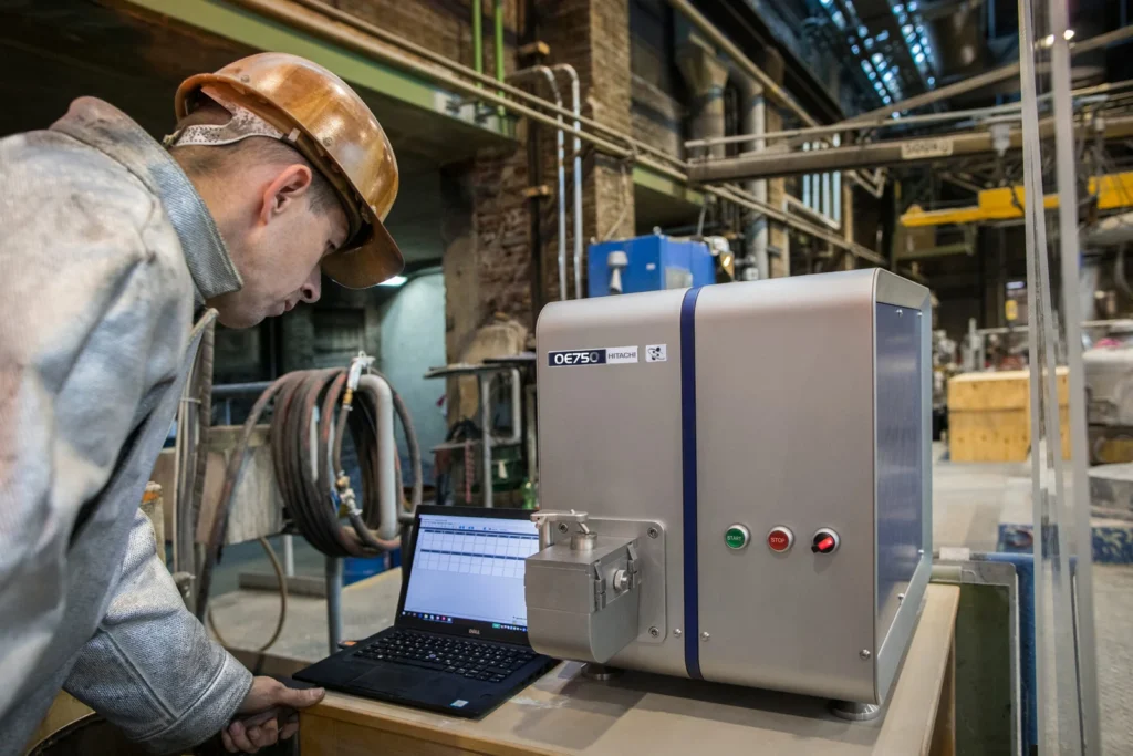 Un ingeniero opera un equipo OES marca Hitachi modelo OE750 conectado a una laptop para procesar datos de fundición pura.