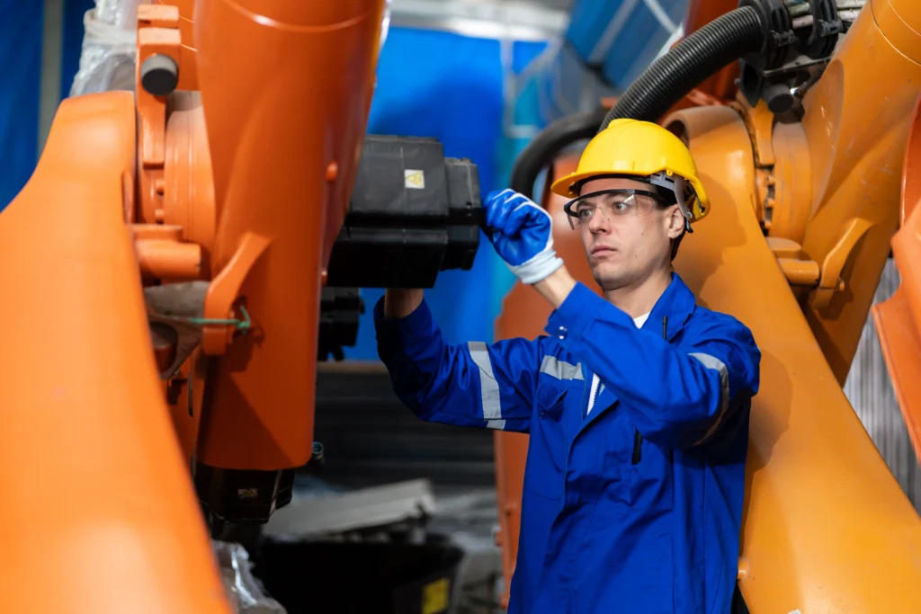 Técnico ajustando brazo robótico industrial como parte de las estrategias de integridad industrial.