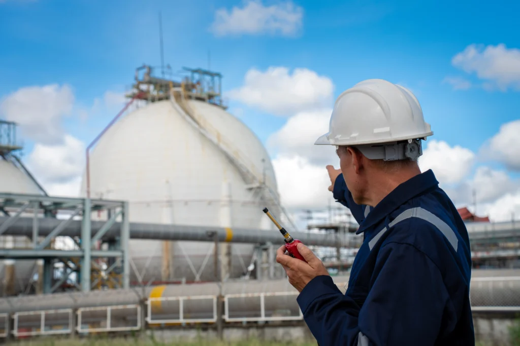 Operario inspeccionando activos industriales críticos en una planta de almacenamiento de gas.