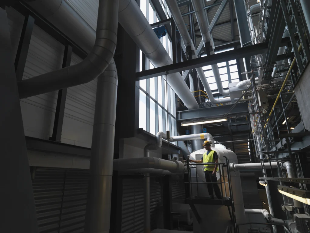 Mantenimiento industrial basado en riesgo: Técnico inspecciona tuberías en la sala de calderas.