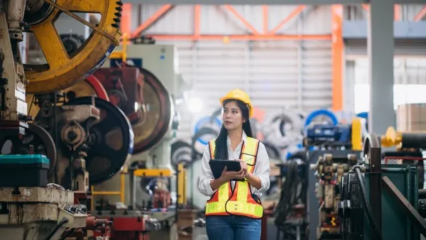 Ingeniera con tableta en planta industrial, gestionando confiabilidad operacional.