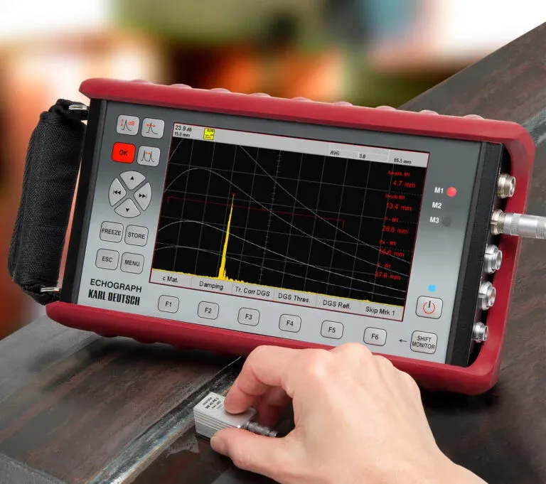 Inspector utilizando un equipo de medición por ultrasonido industrial portátil en una pieza metálica.