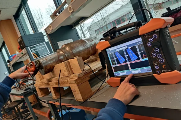 Profesional usando ultrasonido como uno de los tipos de ensayos no destructivos en componentes industriales.