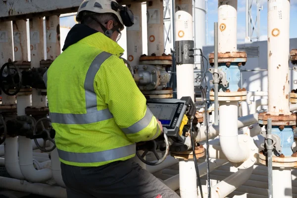 Un técnico especializada en ondas guiadas inspecciona un ducto industrial usando un equipo portátil para detectar fallas.
