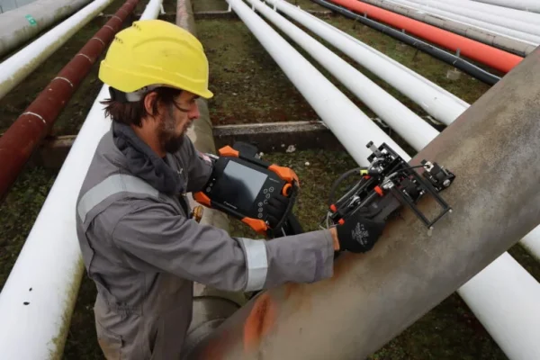 Técnico especializado revisando cómo detectar grietas en estructuras metálicas exteriores con un detector portátil.